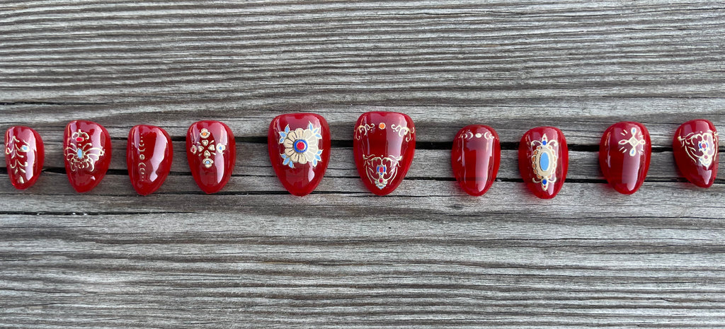 Cursed Heirloom handmade red jelly press on nails with gold filigree charms and jewels, short almond