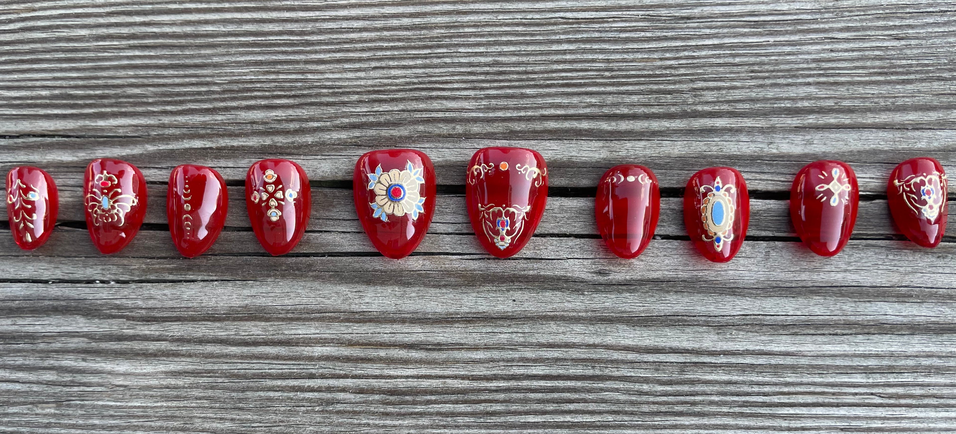 Cursed Heirloom handmade red jelly press on nails with gold filigree charms and jewels, short almond